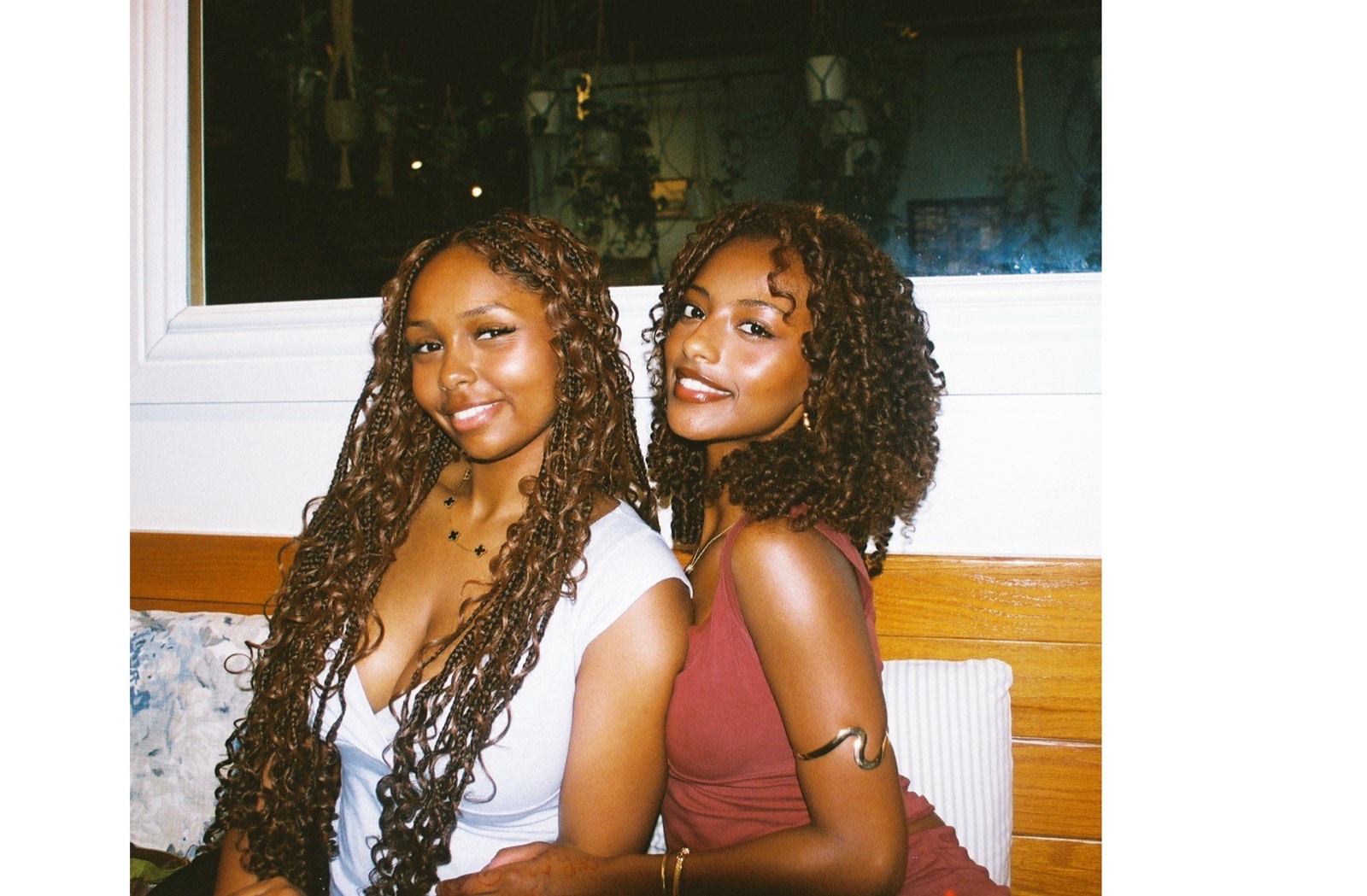 Double portrait of two women seated at a restaurant booth, warm film light