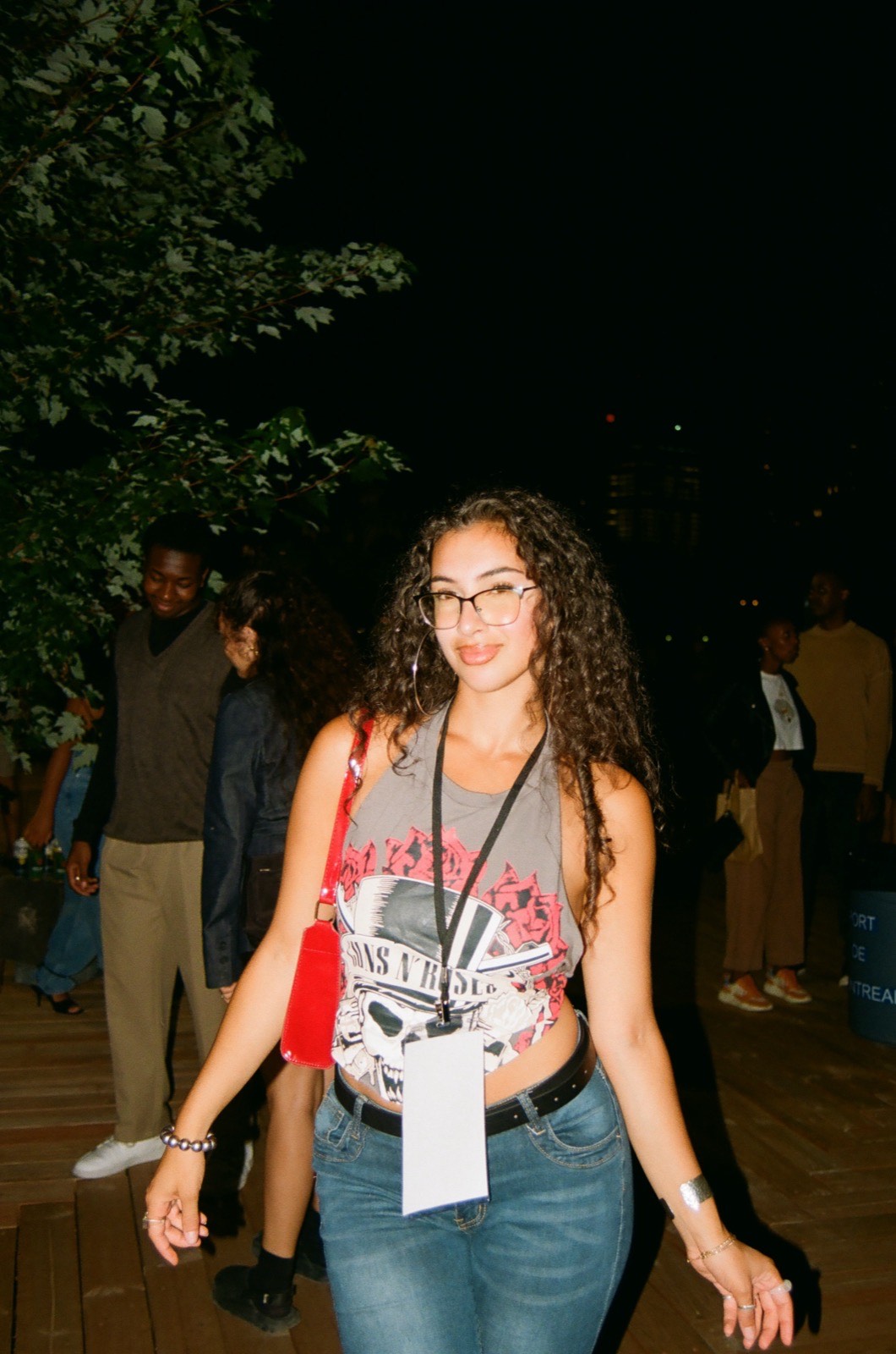 Solo portrait of a woman in a vintage band tee with a press lanyard, downtown at night